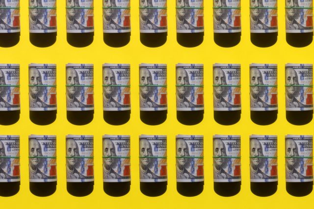 American dollar rolls flat lay on yellow background illustrating increasing American whiskey tariffs