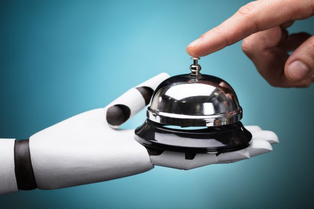 Person's Ringing Service Bell Hold By Robot On Turquoise Background, symbolising AI in hospitality.